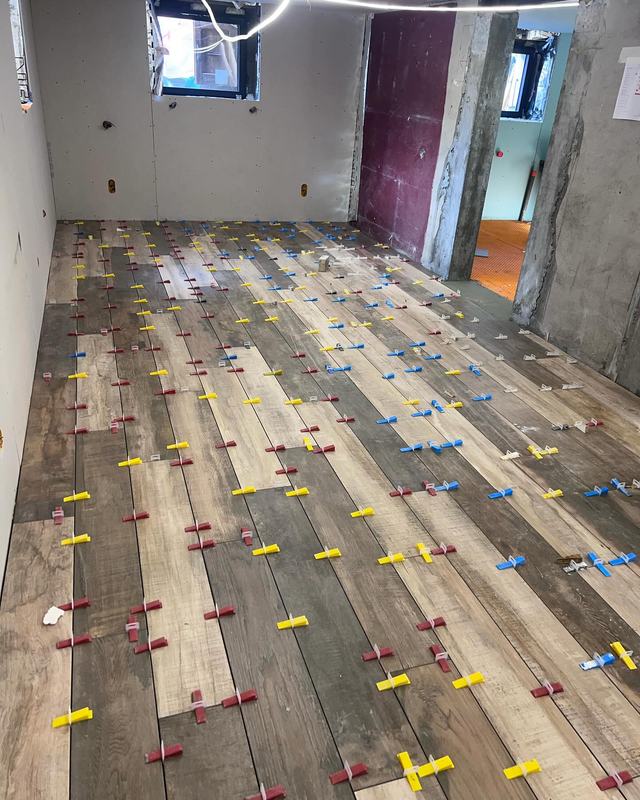 Sol en carreaux effet bois en cours de pose, croisillons de nivellement visibles