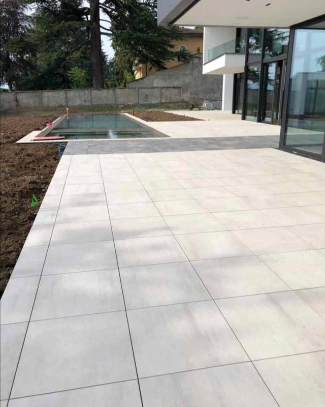 Piscine terminée entourée de dalles claires, devant une maison