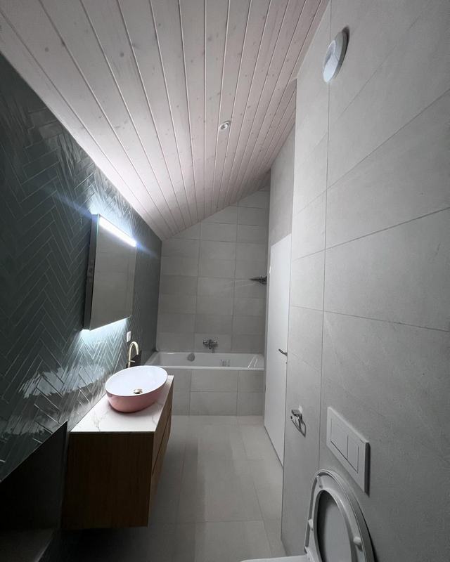 Salle de bain sous toit avec vasque rose et faïence verte